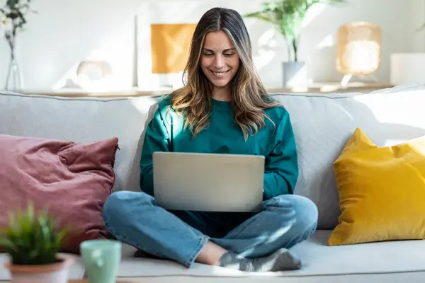 Frau am Laptop sitzt auf Sofa