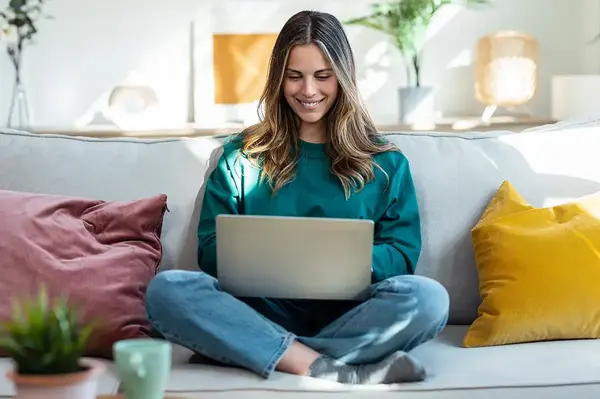 Frau sitzt am auf Sofa mit Laptop